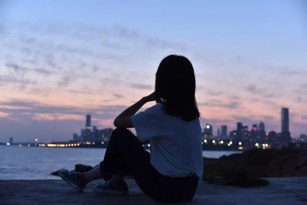 海辺で考え事をしながら景色を眺める女性